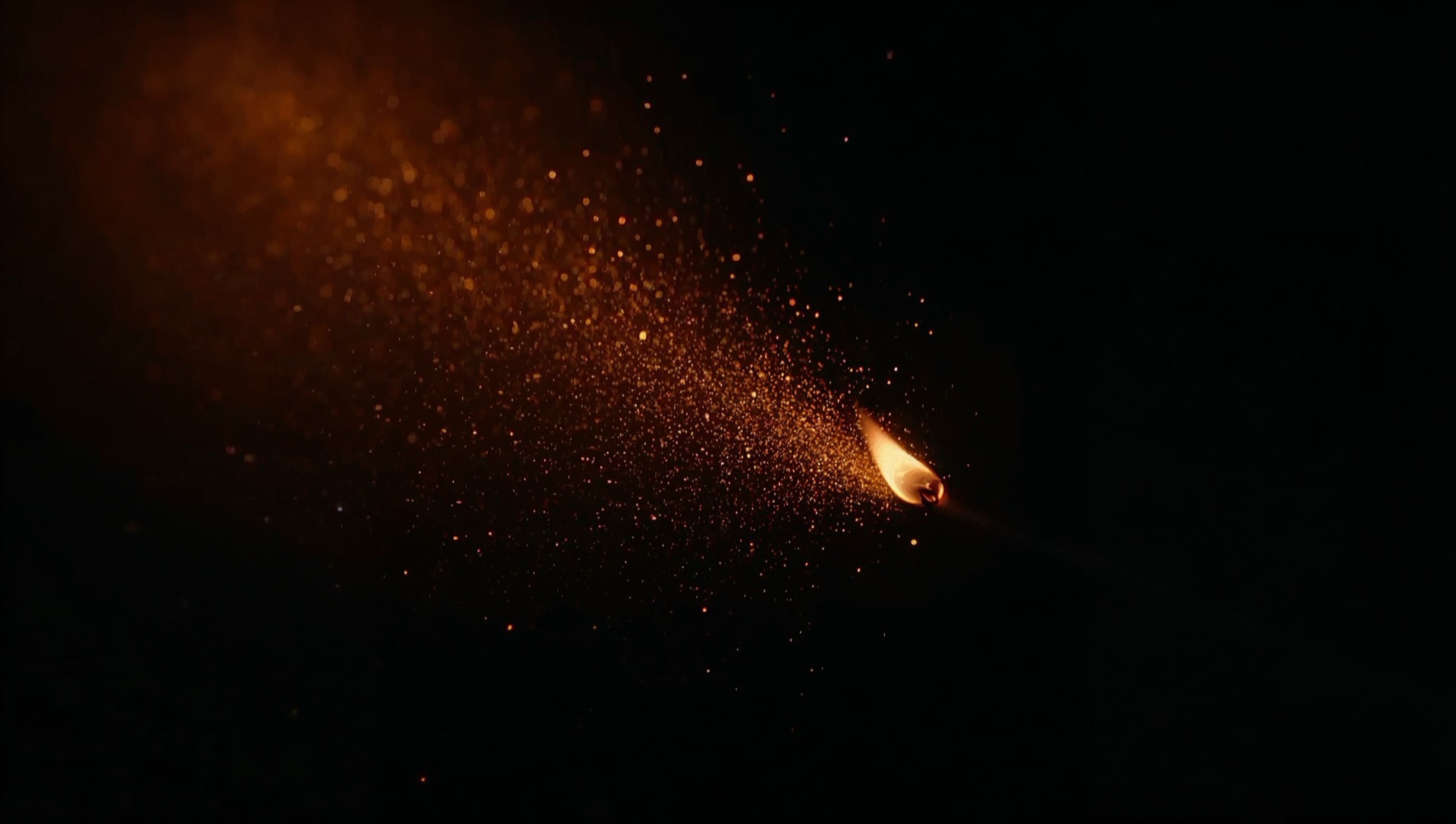 Sparks rising from a struck match in darkness
